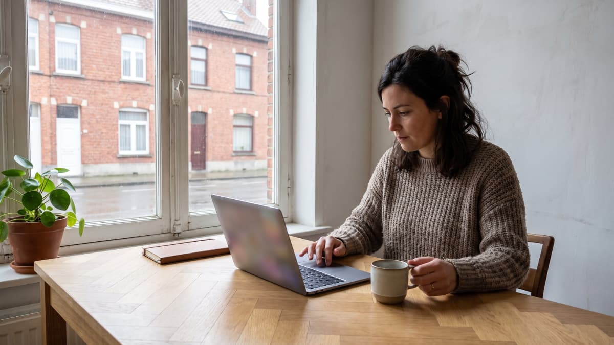 Vrouw bestelt dienstencheques op haar laptop aan de keukentafel